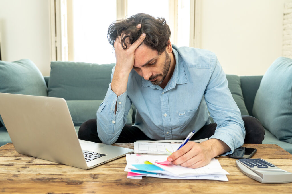 Person creating needs vs wants budget list with calculator and bills